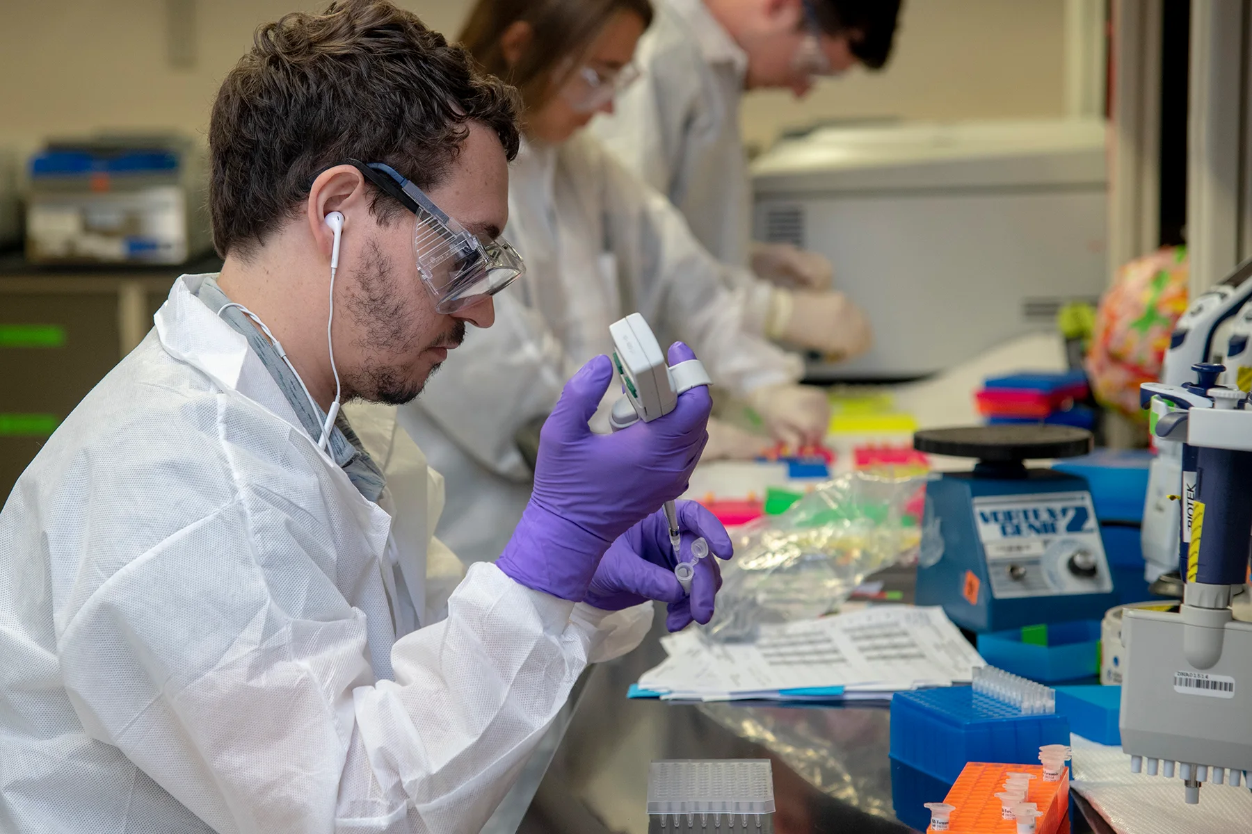 A researcher pipetting samples in a genetics laboratory